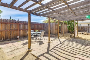 A covered patio area with a wooden pergola, a table with chairs, and a wooden fence in the background. - Orland Home w/ Pool! Near Park, Tennis & Dtwn (Orland)