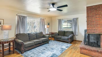 Un salon avec une cheminée, deux canapés, une table basse et un ventilateur de plafond.