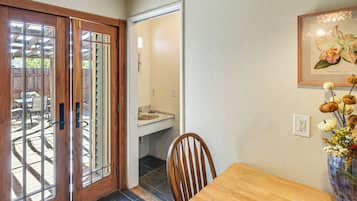 Une table de salle à manger en bois avec une chaise, une porte en bois avec des panneaux de verre, un mur blanc et un tableau encadré.