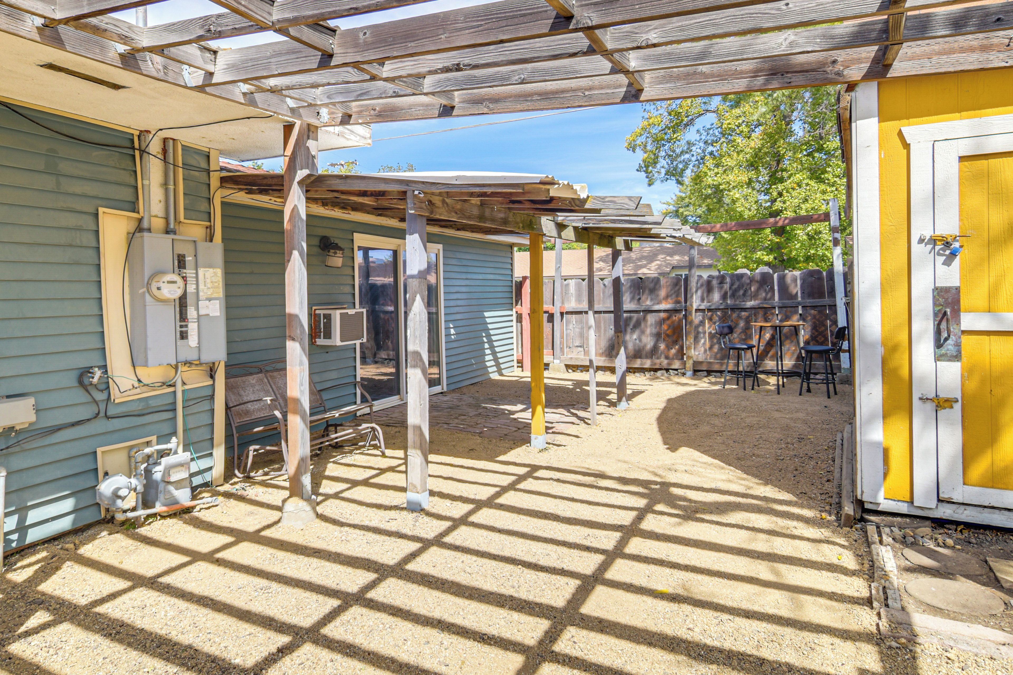 A covered outdoor area with a wooden structure, a yellow door, and a window.