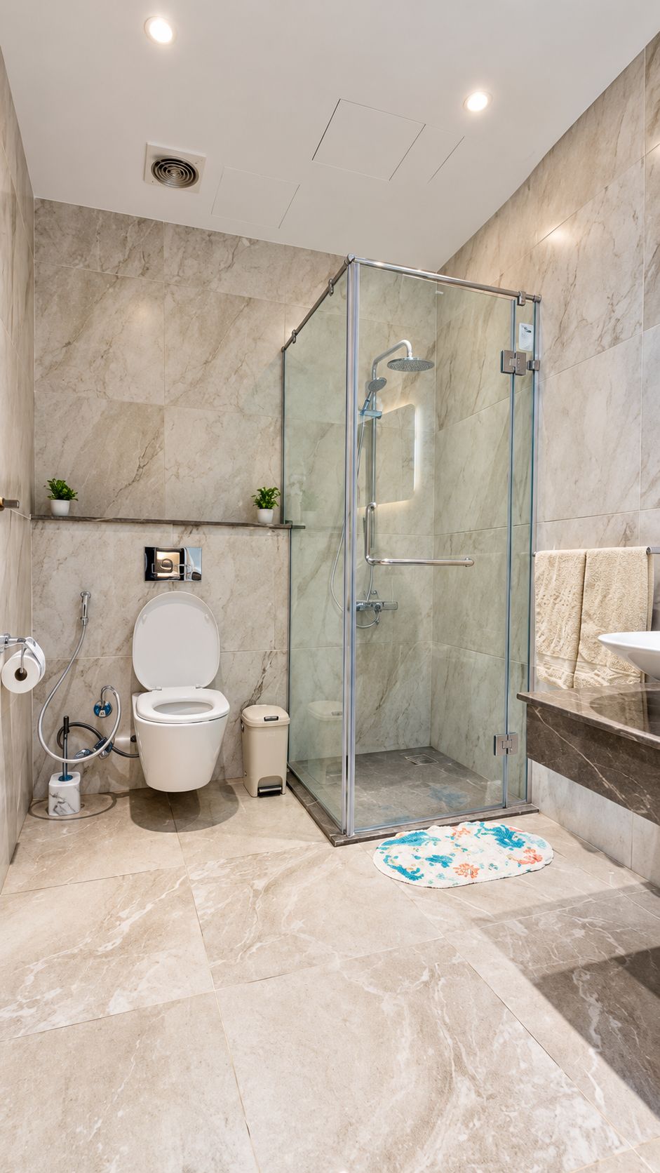 A modern bathroom with a glass-enclosed shower, a toilet, and a sink.