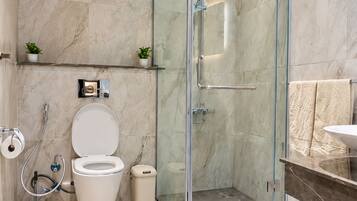 A modern bathroom with a glass-enclosed shower, a toilet, and a sink.