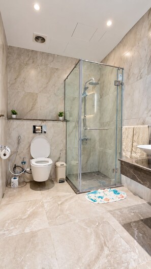 Un baño moderno con ducha envuelta en vidrio, inodoro y lavamanos.