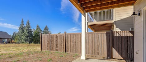 A wooden deck with a covered area, a wooden fence, and a house with a window.
