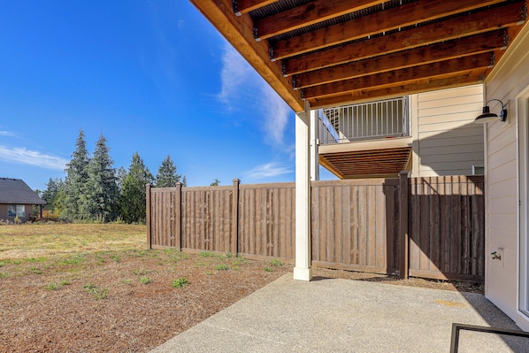 A wooden deck with a covered area, a wooden fence, and a house with a window. - PNW Home Base! Gresham Studio w/ Patio (Gresham)