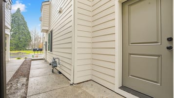 A house exterior with a beige door, a small outdoor utility area, and a clear sky.