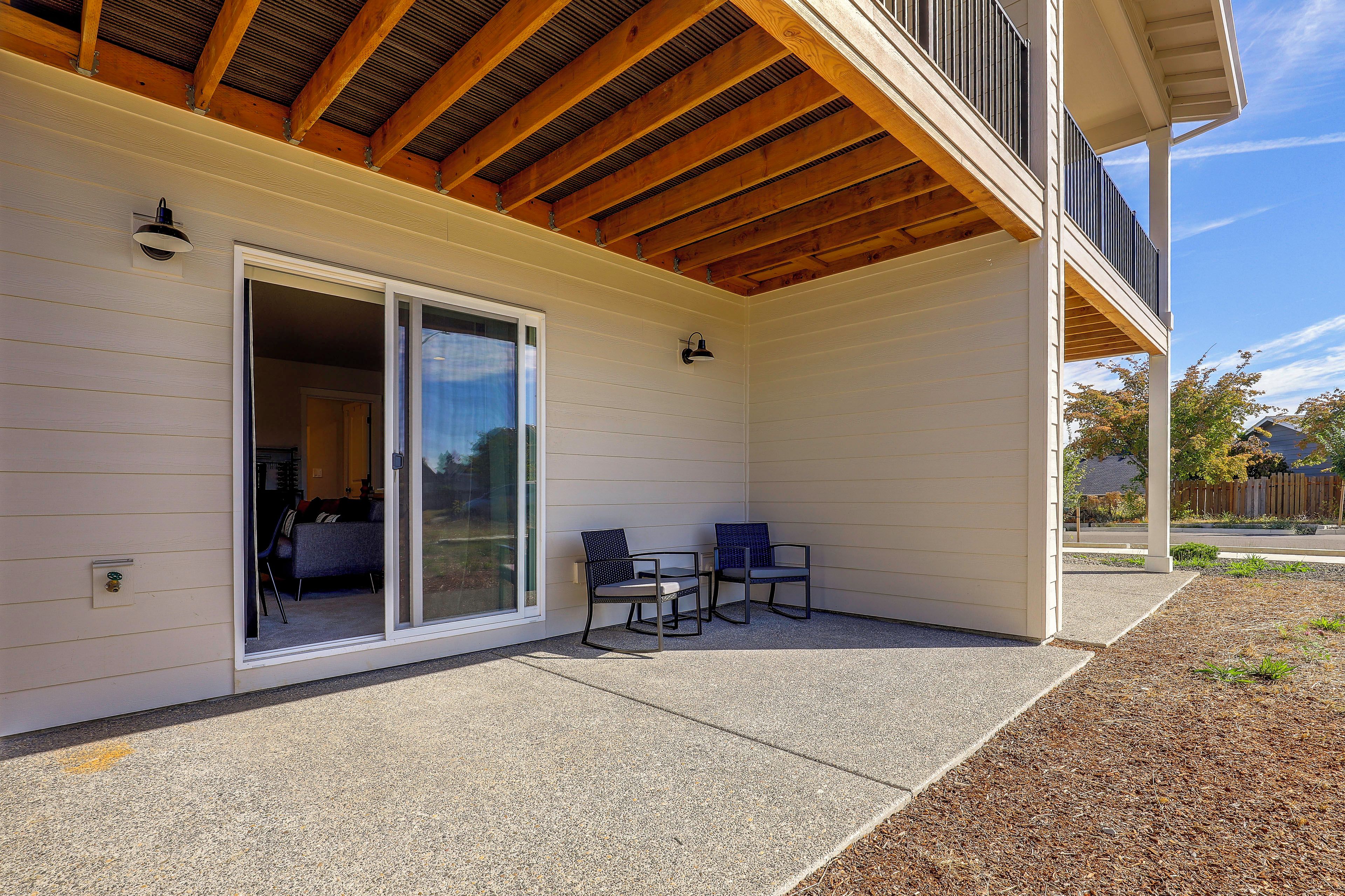 A covered patio with a sliding glass door leading to an interior space, a seating area with two chairs, and a small table.