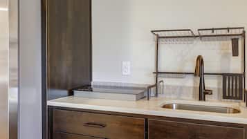 A kitchen with a stainless steel sink, a double hanging rack, and wooden cabinets.