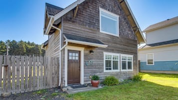 A two-story house with a front porch, a wooden fence, and a small garden.