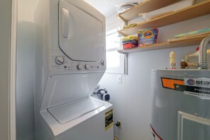 A compact, white front-loading washing machine with multiple settings, a water heater, and a ProLine water heater on the wall. - Rum Away With Me: Resort Pool, Dock + Beach (Clermont)