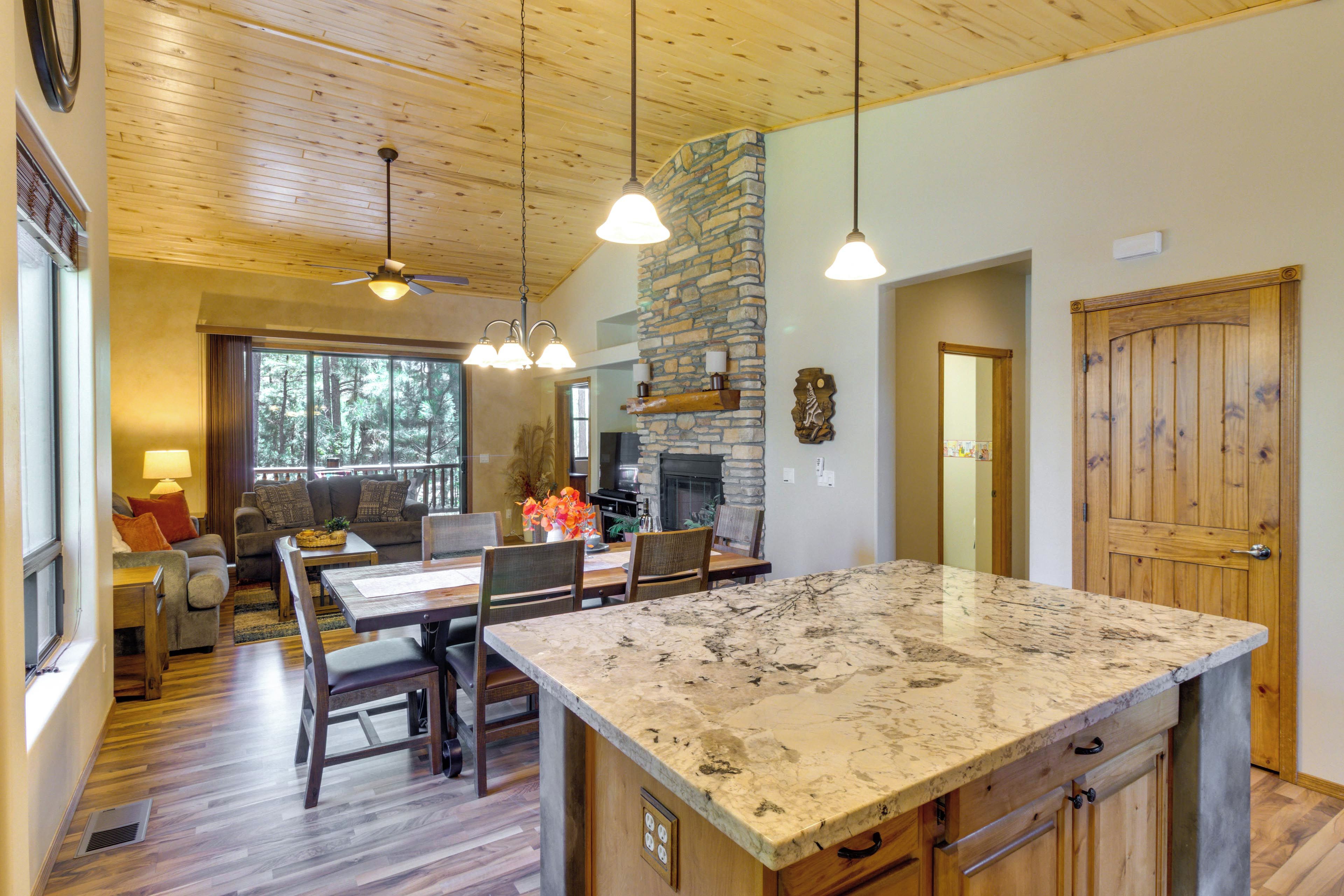 A spacious kitchen with a large island, wooden flooring, and a stone fireplace.
