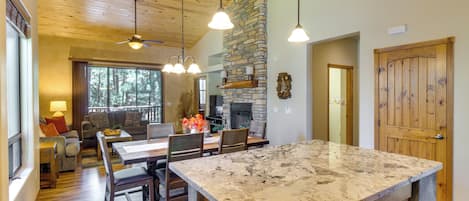 A spacious kitchen with a large island, wooden flooring, and a stone fireplace.