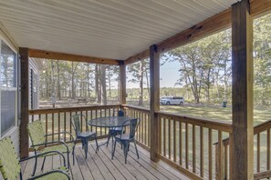 A covered porch with a table and chairs, overlooking a grassy area with trees and a parked car. - Quiet Extended Stay Near Rivanna River (Palmyra)