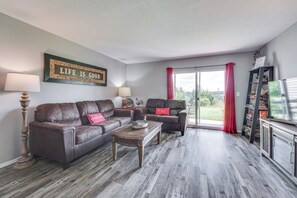 A living room with a brown leather sofa, a wooden coffee table, and a red curtain. - Sleeps 16! Side-by-side Condos Family Friendly (Branson)
