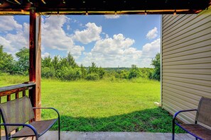 Eine überdachte Terrasse mit Blick auf ein grünes Feld und Bäume.