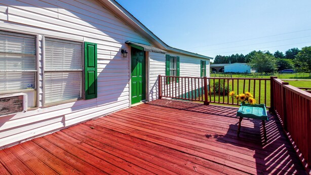 Uma casa com deck vermelho, porta verde e caixa de correio.
