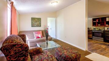 A living room with a sofa, a coffee table, and a painting on the wall.