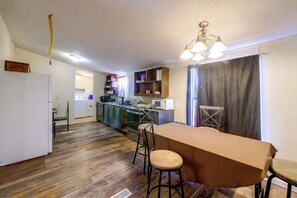 A compact kitchen with a dining area, wooden flooring, and a ceiling light fixture.