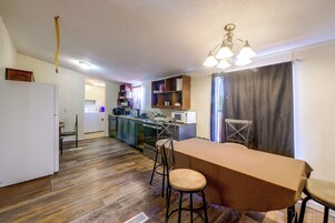 Cozinha compacta com área de refeições, piso de madeira e luminária no teto.