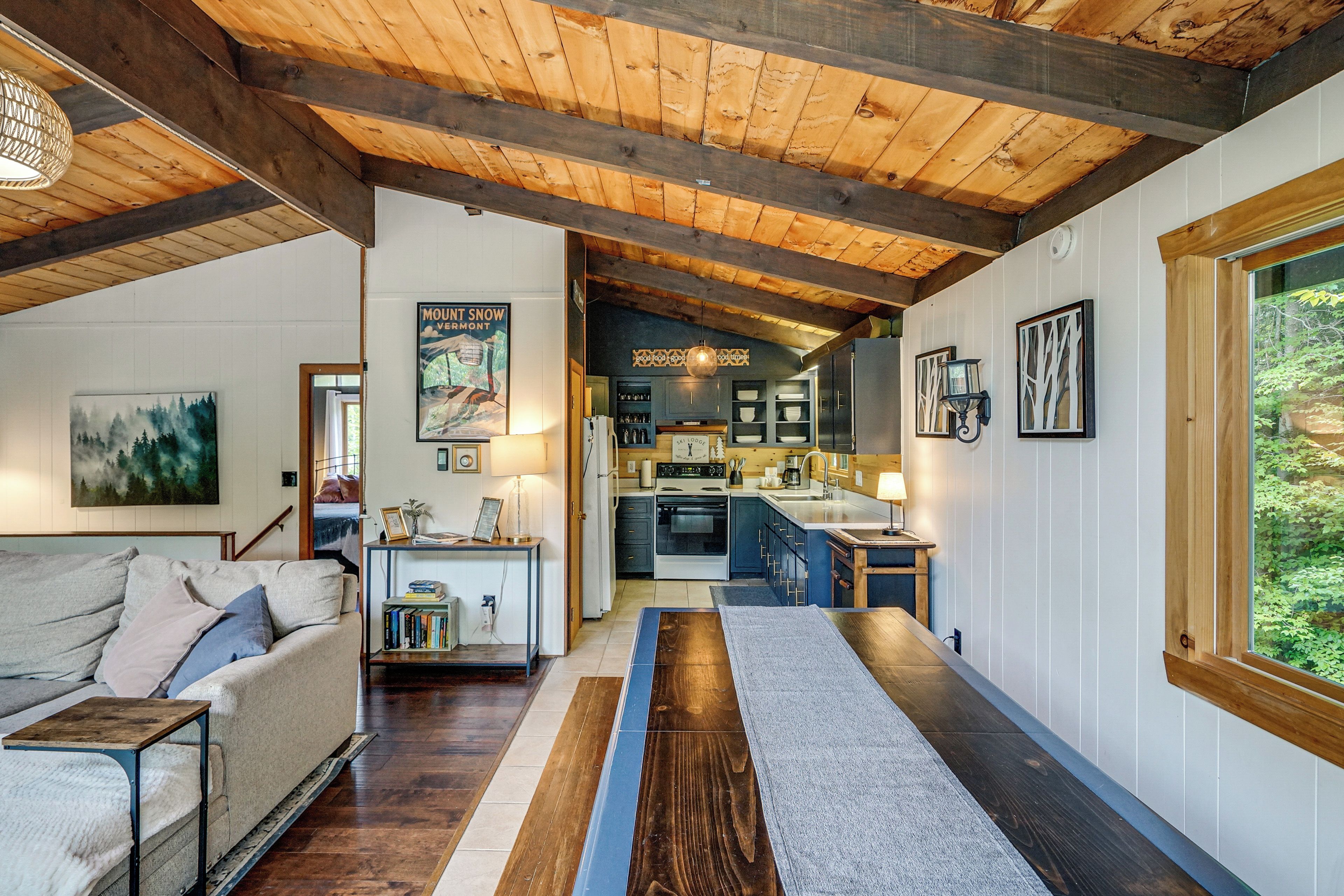 Un interior acogedor con techo de madera, una zona de cocina y un espacio de estar con sofá y mesa de centro.