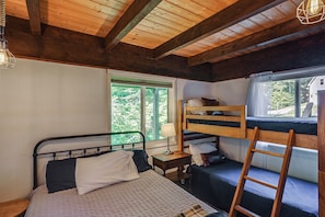 A bedroom with a bunk bed, a single bed, a bedside table with a lamp, and a window with a view of greenery. - Great for Groups! Wilmington Gem w/ Game Room (Wilmington)