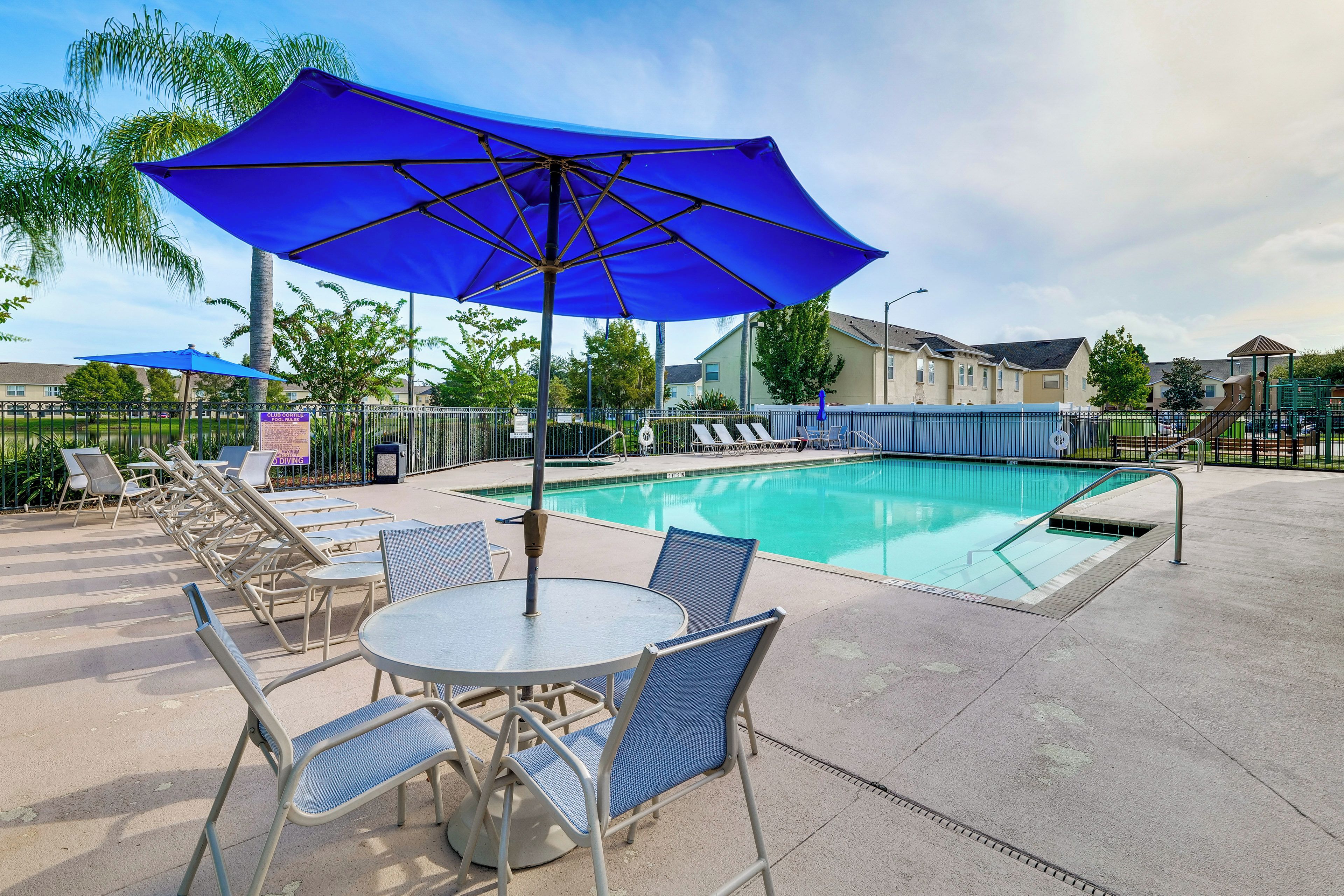 A swimming pool area with lounge chairs and umbrellas.