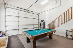A pool table in a room with a garage door, a refrigerator, and a wooden staircase. - Hot Tub & Mtn Views! Big Bear All-seasons Escape (Big Bear City)