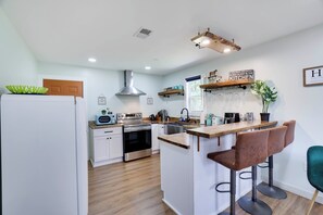 A modern kitchen with a central island, bar stools, a built-in oven, and a variety of appliances. - Walk to Shops & Dining! Poconos Family Getaway (Tannersville)