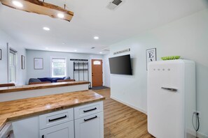 A modern kitchen with wooden countertops, a white refrigerator, and a flat-screen TV mounted on the wall. - Walk to Shops & Dining! Poconos Family Getaway (Tannersville)
