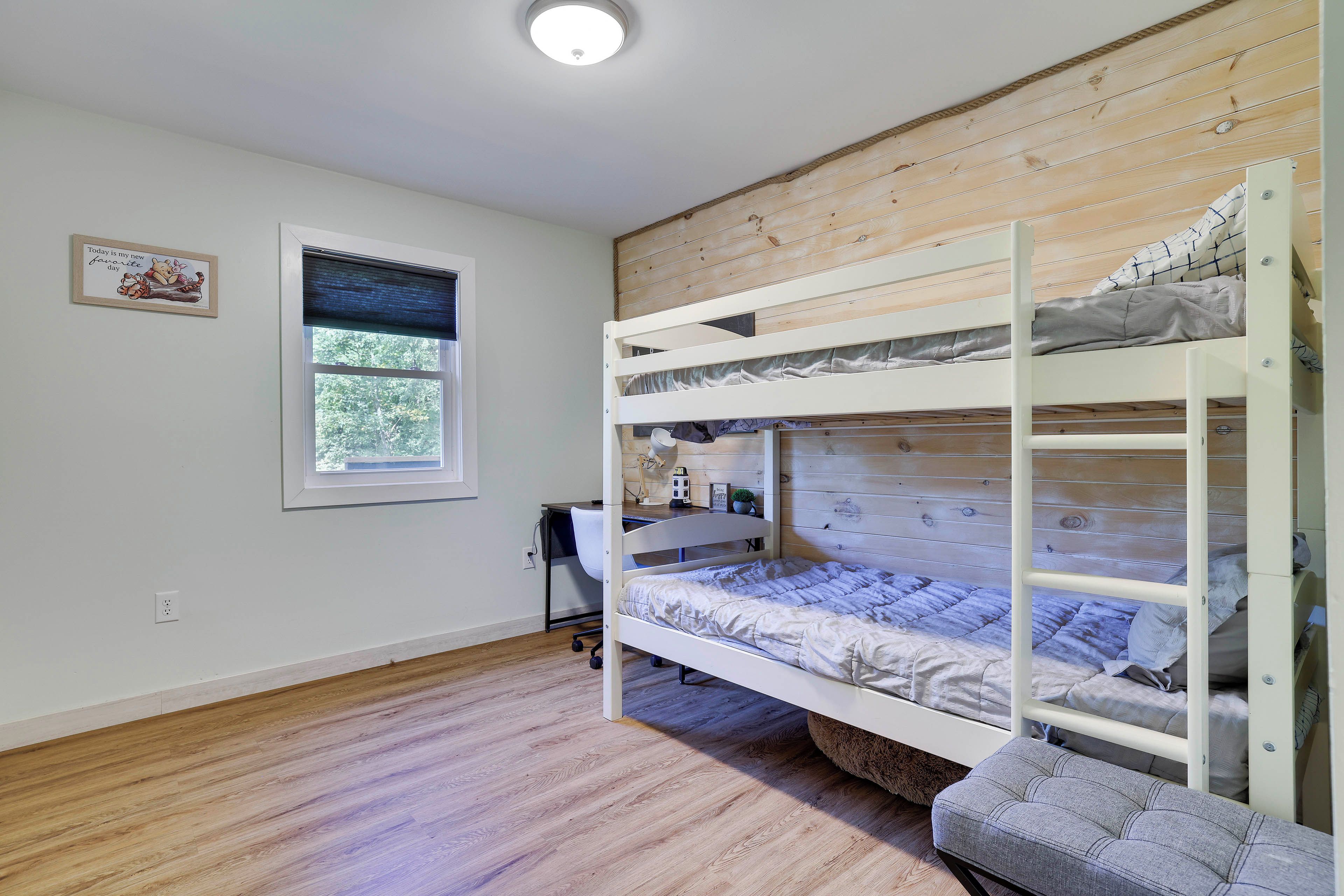 Ein Mehrbettzimmer mit Fenster, Schreibtisch und Stuhl.