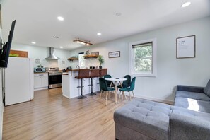 A modern kitchen with a central island, bar stools, and a dining table with chairs. - Walk to Shops & Dining! Poconos Family Getaway (Tannersville)