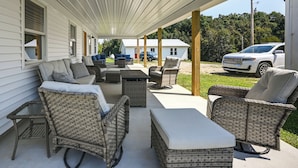 A covered patio area with wicker furniture and a white SUV parked outside. - The Minnie House: Farm Retreat Near Cambridge (Pleasant City)