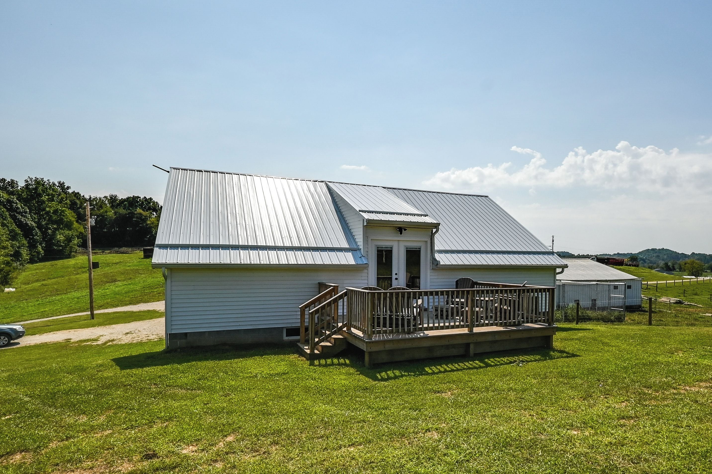 A small white building with a metal roof and a wooden deck.