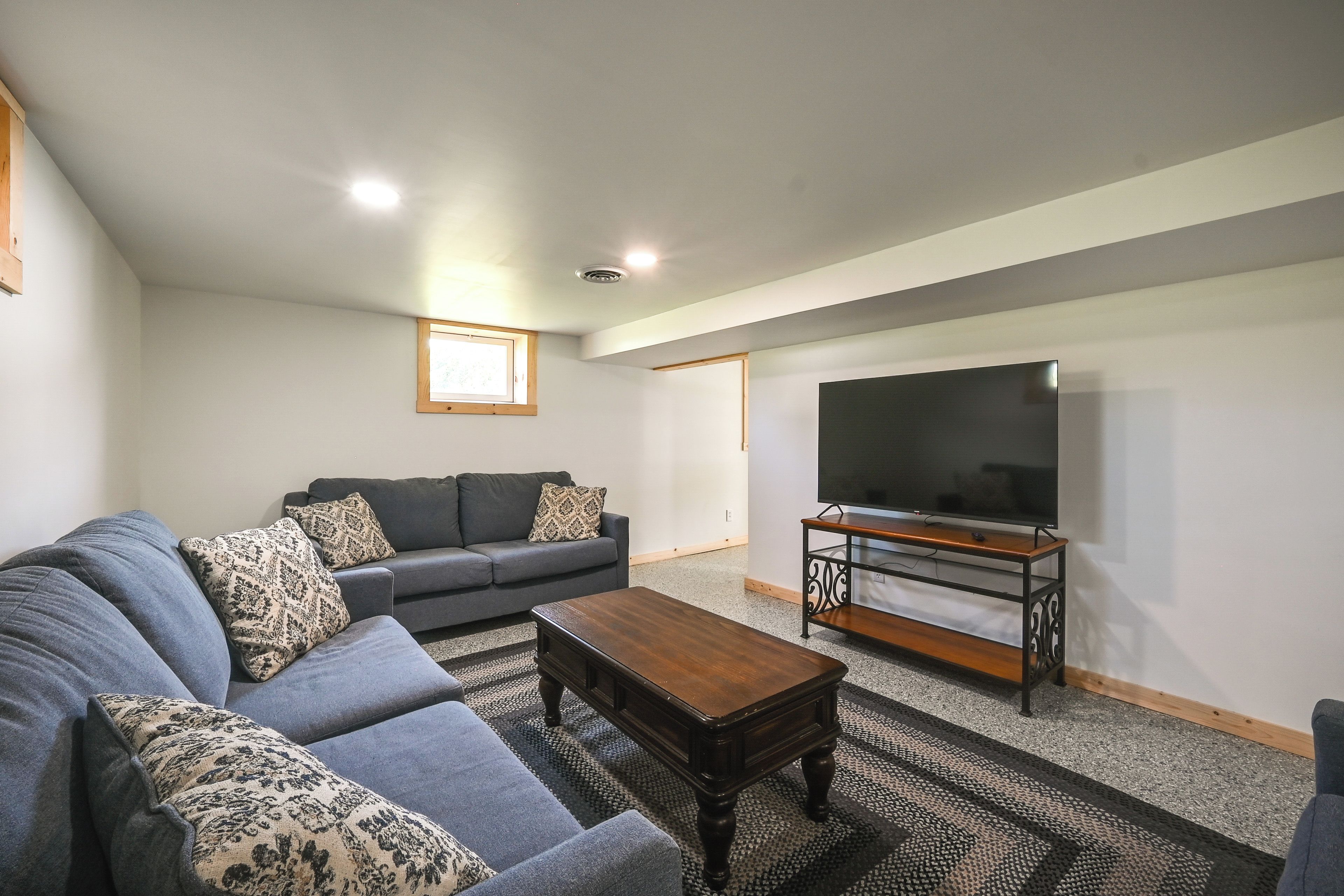 A living room with a sofa, a coffee table, a TV on a stand, and a window.
