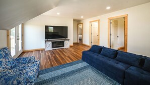 A spacious living area with a flat-screen TV, a blue sofa, and a patterned rug. - The Minnie House: Farm Retreat Near Cambridge (Pleasant City)