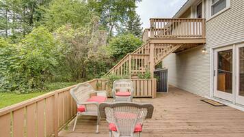 A wooden deck with wicker furniture and a wooden staircase leading to a decked area.