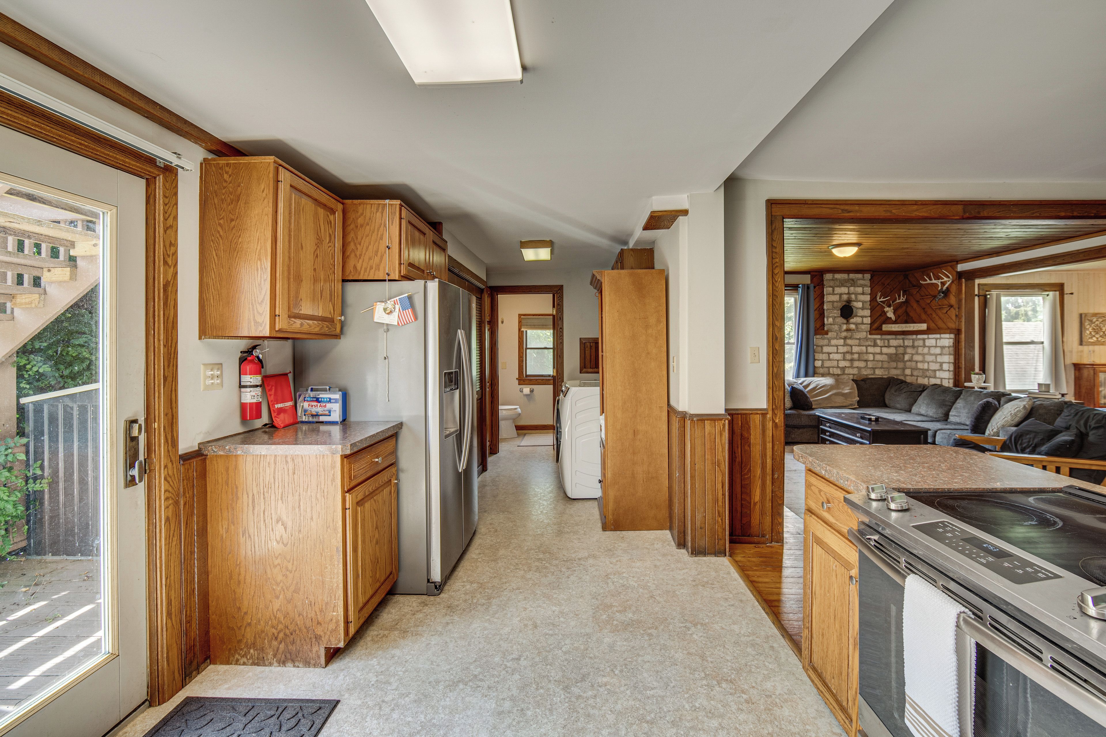 A compact kitchen with wooden cabinets, a refrigerator, a stove, and a sink.
