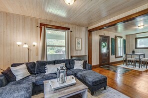 A cozy living room with a sectional sofa, a coffee table, and a dining area with a table and chairs.
