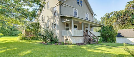 A two-story house with a front porch and a small staircase leading to the entrance.