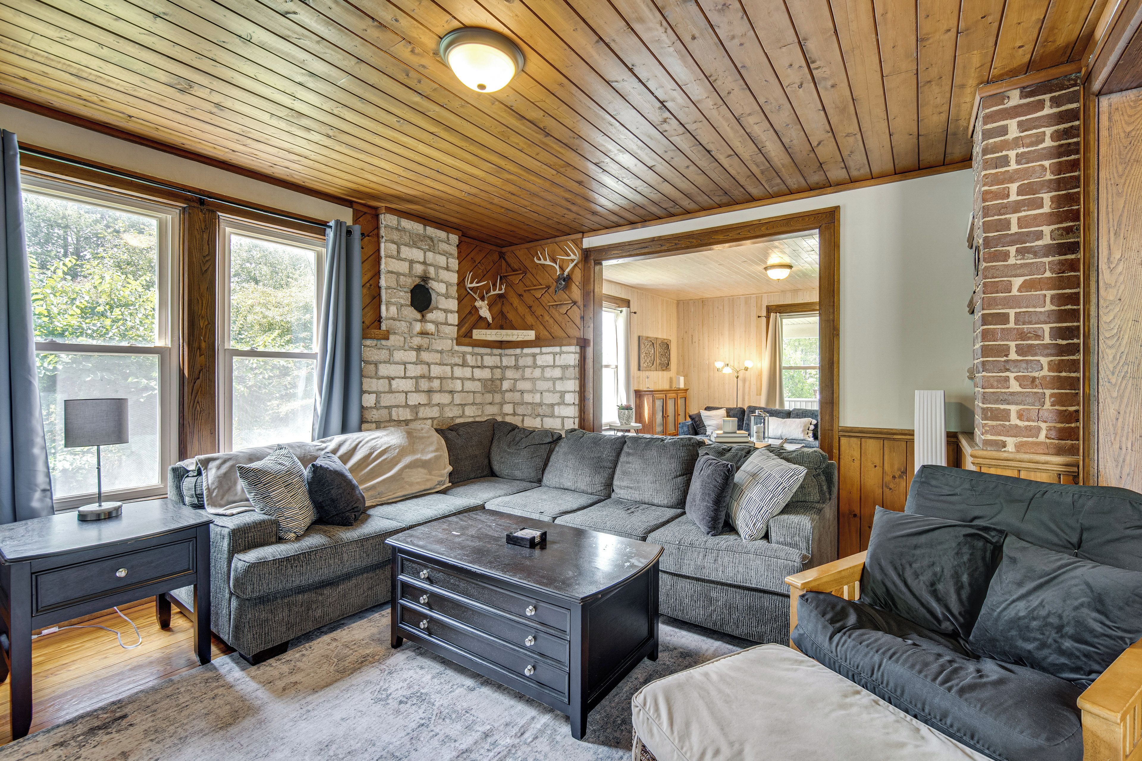 A cozy living room with a sectional sofa, a coffee table, and a fireplace with a deer skull decoration.