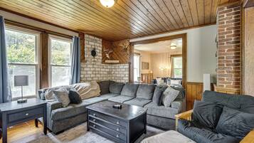 A cozy living room with a sectional sofa, a coffee table, and a fireplace with a deer skull decoration.