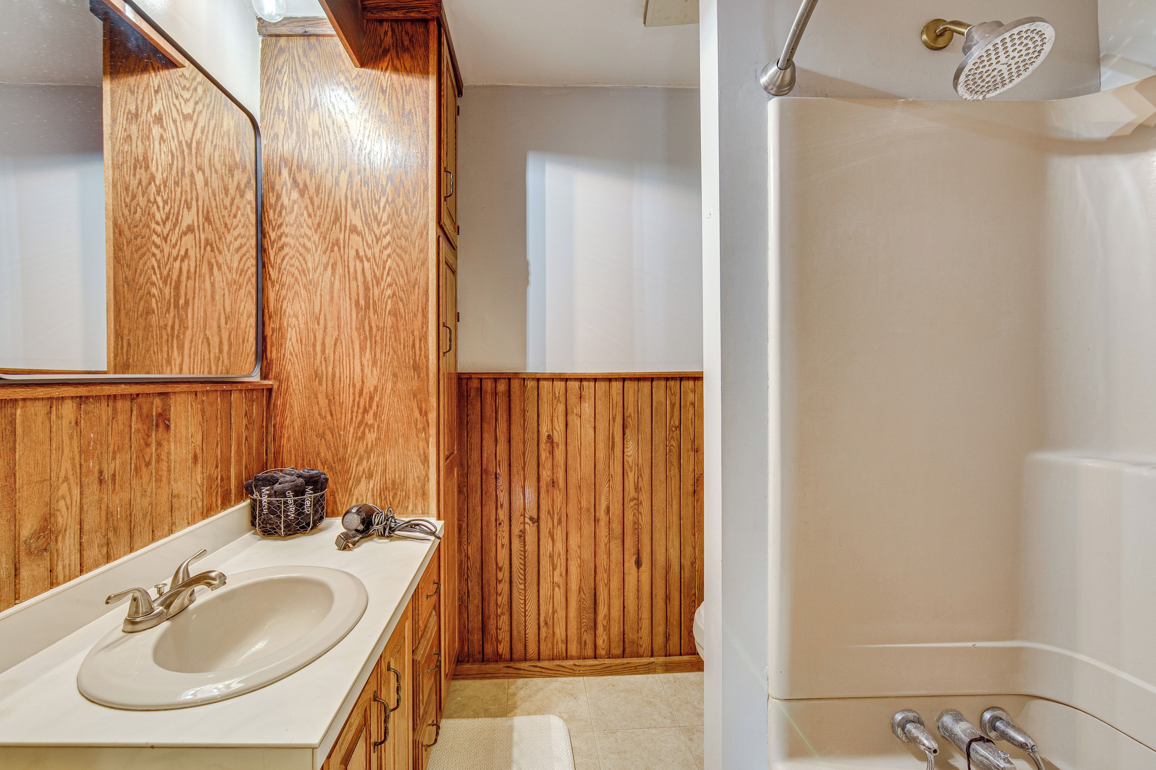 Une salle de bain avec un meuble-lavabo en bois, un évier et une douche.