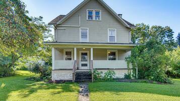 A two-story house with a front porch, a stone pathway leading to the entrance, and a well-maintained lawn.
