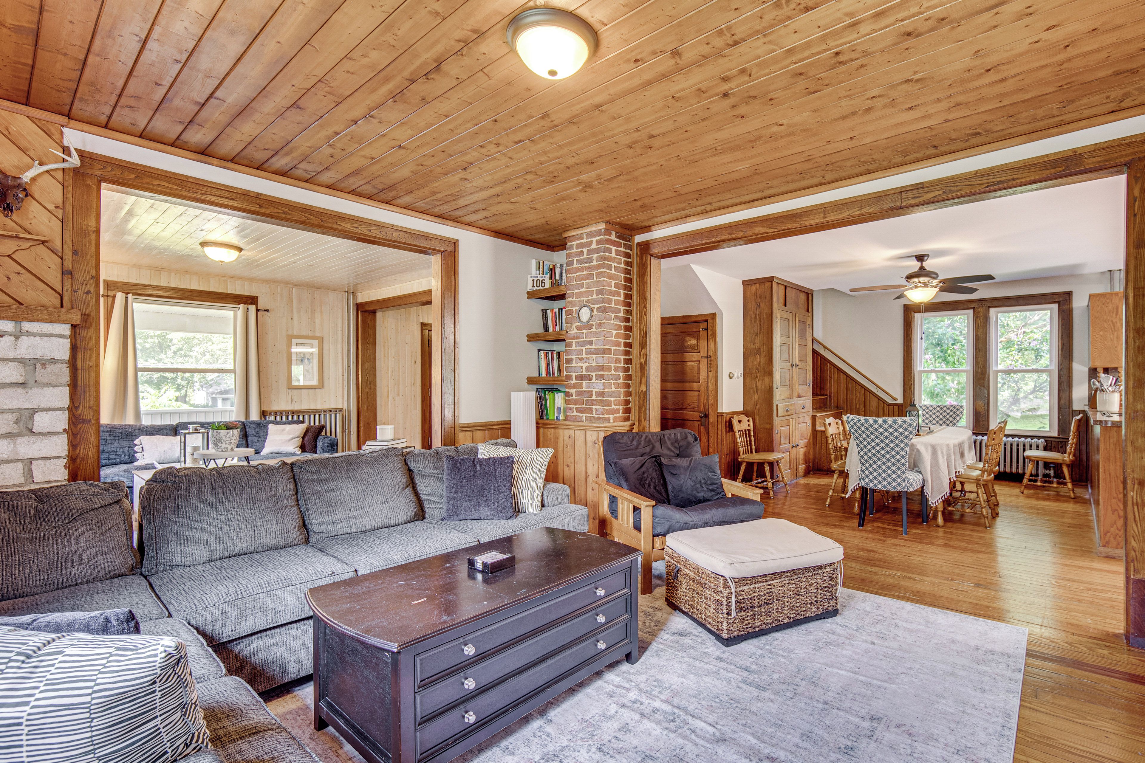 A spacious living room with a wooden ceiling, a fireplace, and a dining area with wooden furniture.