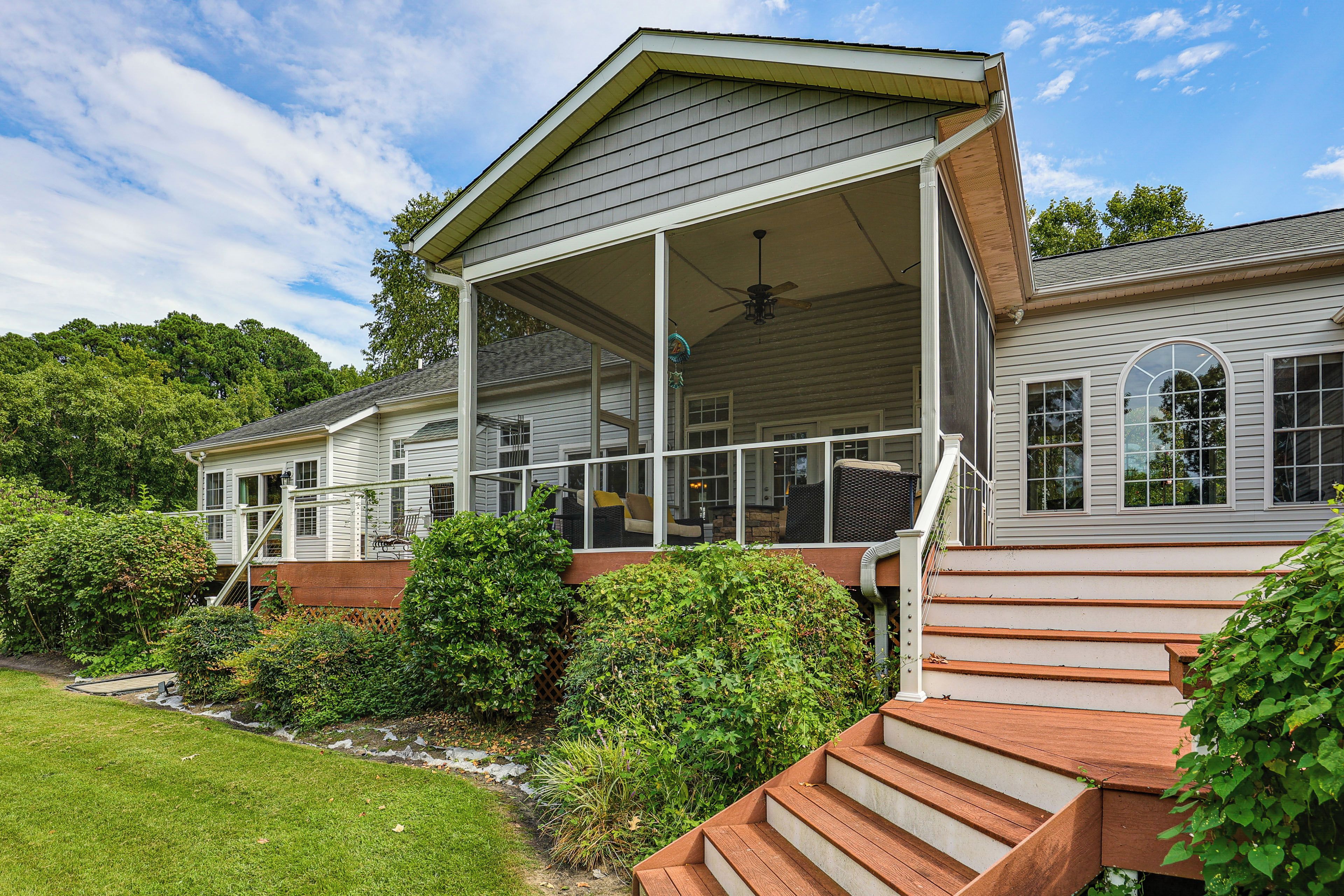 A two-story house with a covered porch, a staircase leading to the upper level, and a well-maintained garden.