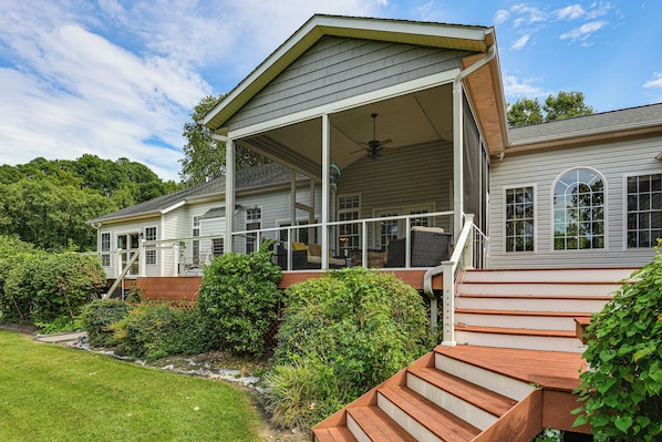A two-story house with a covered porch, a staircase leading to the upper level, and a well-maintained garden.