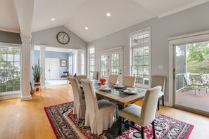 A spacious dining area with a large table, multiple chairs, and a view of the outdoors through large windows.