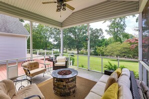 A covered outdoor patio with a fire pit, seating area, and a view of the backyard.