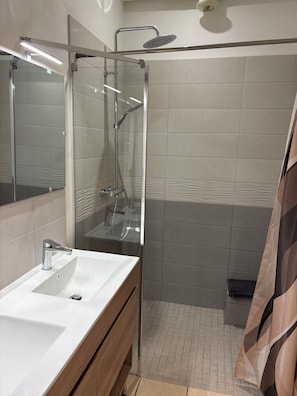 A modern bathroom with a glass-enclosed shower, a white sink, and a mirror. - 1-Bedroom Apartment in the Heart of the Combrailles (Pionsat)