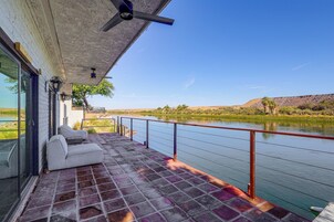 Un balcón con vistas a un río, un sofá blanco y un ventilador de techo.